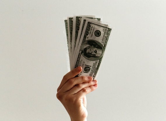 Hand holding a fan of hundred dollar bills
