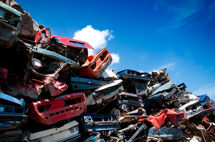 Pile of crushed junk cars against a blue sky