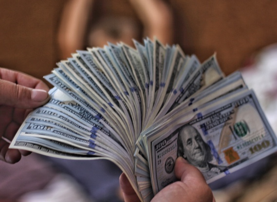 Hands fanning out a stack of hundred dollar bills